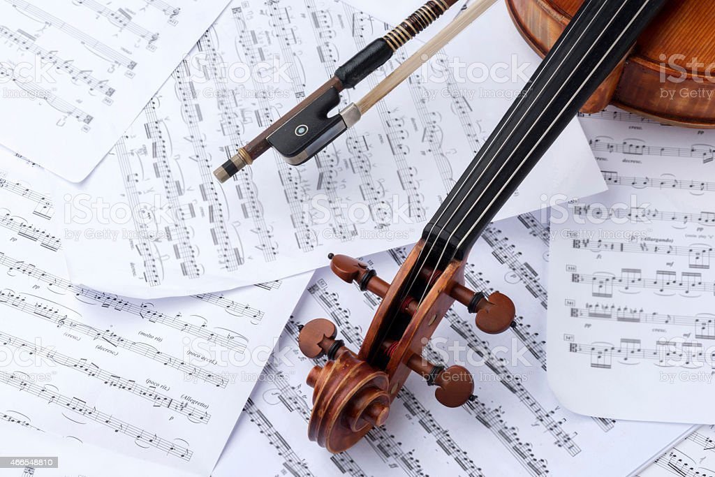 close-up of a violin and bow, with sheet music in the background